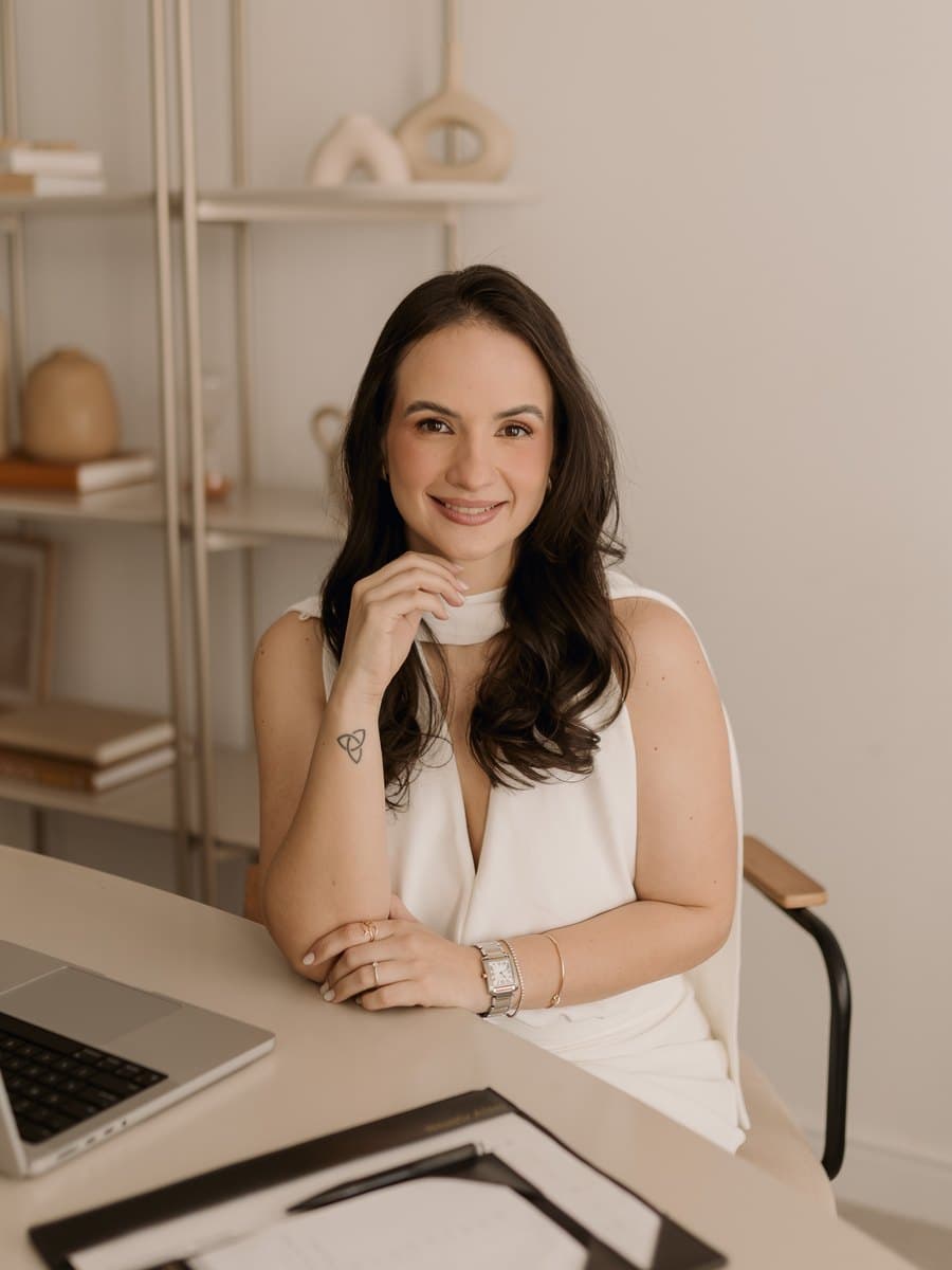 Beatriz Aires, nutricionista clínica, sentada à mesa com notebook e prancheta