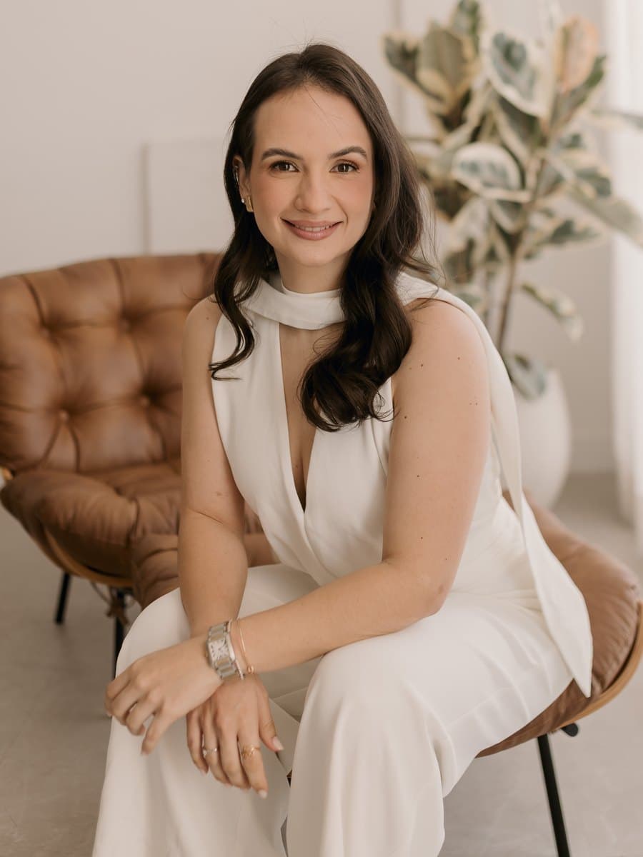 Beatriz Aires, nutricionista, sentada em uma poltrona de couro e sorrindo